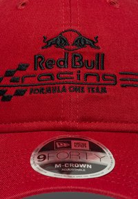 Κόκκινο καπέλο με κεντημένο λογότυπο «Red Bull Racing Formula One Team» σε μαύρο, με επίπεδη γείσο και ρυθμιζόμενο ιμάντα, κατασκευασμένο από υφασμάτινη υφή.