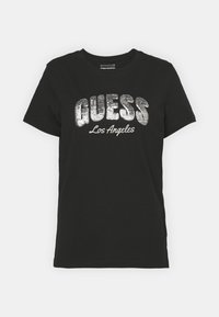 Sort bomulds T-shirt med iøjnefaldende metallisk sølv "GUESS" logo med "Los Angeles" under, kort ærmer og rund halsudskæring.