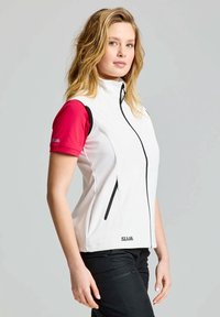 Weißes ärmelloses Jackett mit schwarzen Akzenten und Reißverschluss, kombiniert mit einem kurzärmeligen rosa Hemd. Glatter Stoff, ergonomische Passform und lässiges Design.