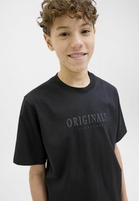 Černé bavlněné tričko s krátkým rukávem. Na přední straně má nápis "ORIGINALS JACK&JONES" v vyvýšeném písmu. Jednoduchý design.