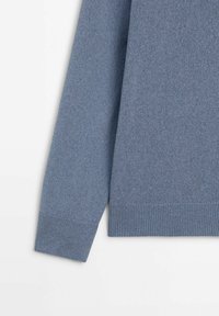 Pull bleu en maille à manches longues avec poignets et ourlet côtelés sur fond blanc.