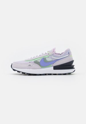 Jasnofioletowe i zielone buty Nike z białymi sznurowadłami, niebieskim logo Nike, czarną warstwową podeszwą oraz detalami z siateczki i zamszu na cholewce.