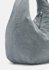 Torebka hobo wykonana z teksturowanego szarego denimu. Posiada zamek błyskawiczny oraz wytłoczone logo marki z boku. Miękka, luźna konstrukcja.