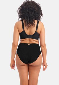 Zwart lingerieset met een bh met verstelbare bandjes en haaksluiting, gecombineerd met high-waisted ondergoed, dat de zachte stoftextuur benadrukt.