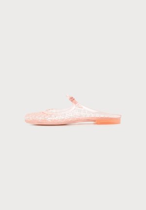 Chaussure plate rose transparente à enfiler avec un motif tissé et une petite bride réglable sur un fond uni.