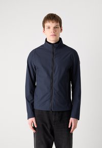 Mornarsko modra zip-up jakna iz vodoodporno tekstila, ki ima visok ovratnik, stranske žepe in gladko teksturo.