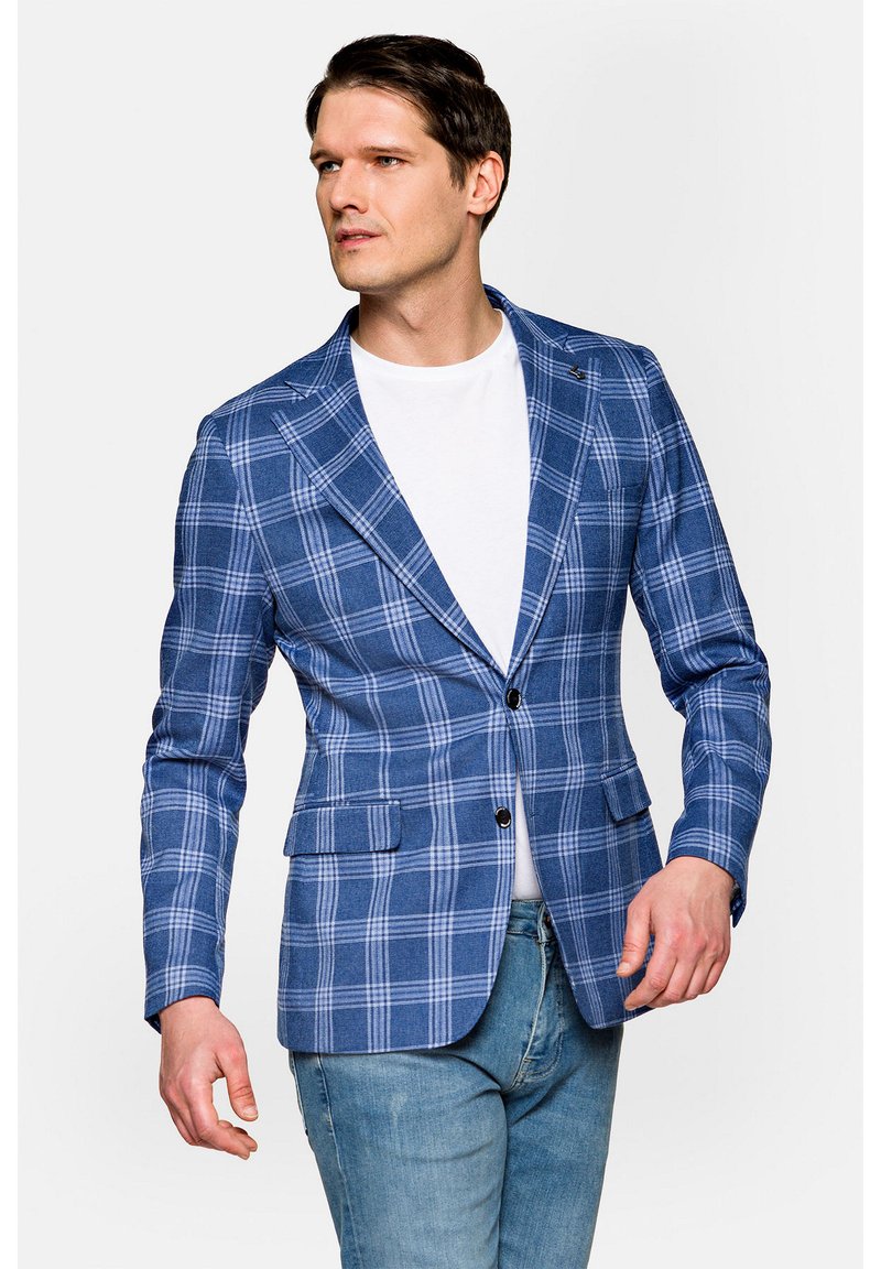 Niebieska marynarka w kratę o dopasowanym kroju, z zapięciem na dwa guziki, klapami typu notch oraz bocznymi kieszeniami. Noszona na białym t-shircie.