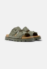 Green rubber sandals featuring two wide straps with adjustable buckles, a thick sole with a textured pattern, and a brown footbed.