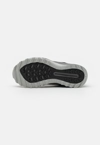 Suola di scarpe sportive nere con un resistente battistrada in gomma per la trazione, con un accento grigio attorno al perimetro e dettagli del logo.