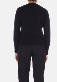Maglione nero a maniche lunghe con orlo a coste testurizzate e corpo liscio. Presenta un collo rotondo e una silhouette aderente. Adatto per essere indossato a strati.