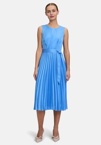 Ein ärmelloses, hellblaues Kleid mit einem plissierten Rock, einem Bindegürtel in der Taille und einer glatten, satinähnlichen Textur.