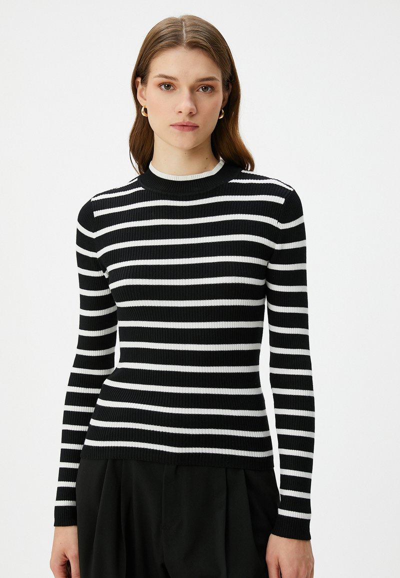 Mustavalkoinen raidallinen neulepaita, jossa on ribbitekstuuri, pyöreä kaula-aukko ja pitkät hihat. Raidat ovat yhtä leveitä.