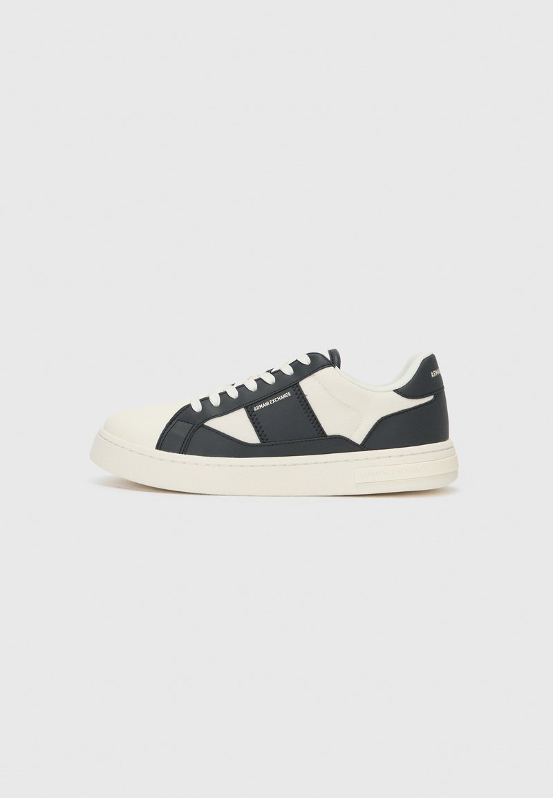 Sorte og kremfargede sneakers med en glatt skinn-overdel, kontrasterende paneler, rund tå, flate lisser og en teksturert gummisåle.