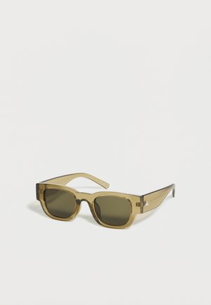Lunettes de soleil rectangulaires teintées vert avec des montures épaisses translucides vert olive reposant sur une surface blanche.
