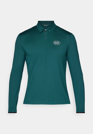 Dark green long-sleeve polo shirt with a subtle textured pattern, half-zip collar, and a circular logo on the left chest.