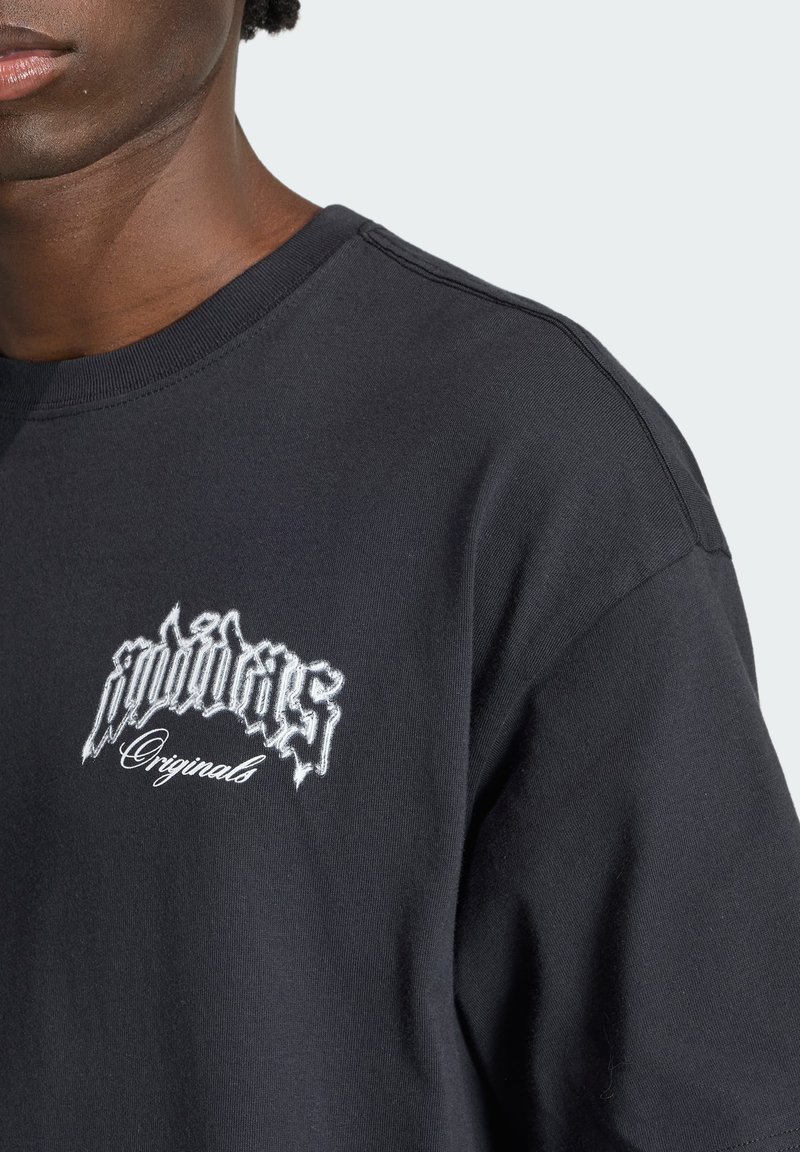 Persona que lleva una camiseta negra de cuello redondo con texto bordado en blanco que dice "pointers Originals" en el pecho izquierdo.