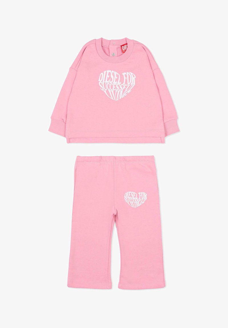 Różowy bawełniany dres z bluzą z długim rękawem ozdobioną białym tekstem w kształcie serca oraz pasujące spodnie z elastycznym stanem.