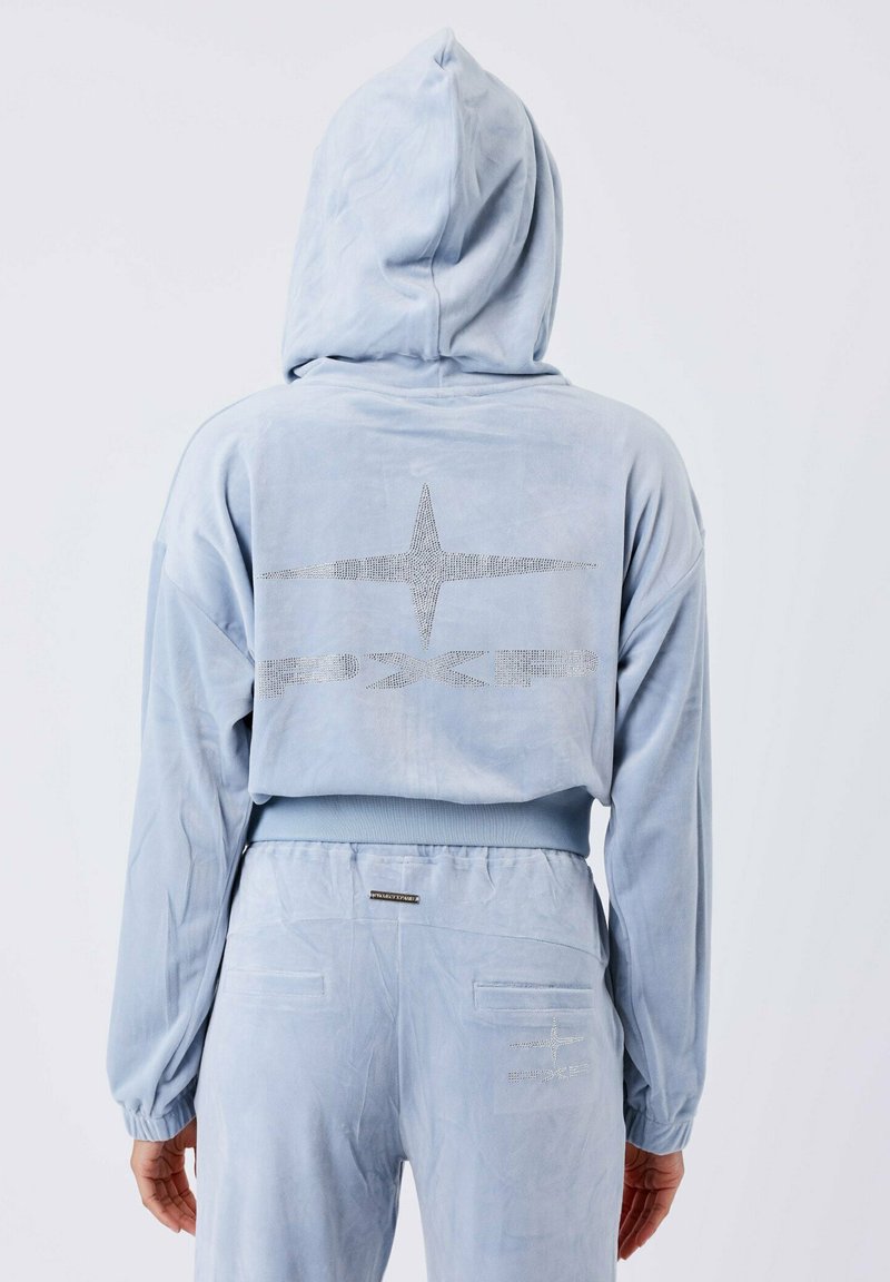 Giocattolo blu chiaro con cappuccio e texture di velluto. Presenta un design di strass a forma di stella sul retro e polsini elastici sui polsi e in vita.