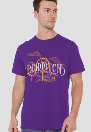 Man wearing purple T-shirt with Quidditch text, golden Snitch wings, hoops, and crossed broomsticks design on front.