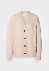 Cardigan en maille beige avec un col en V, quatre boutons foncés, deux poches avant et des poignets et un bas côtelés.