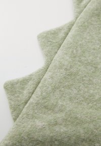 Zöld textil, puha tapintással, nyers szélekkel és finom heather mintázattal. A felülete kissé bolyhosnak tűnik.