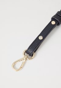 Navy nahkavyö, jossa on strukturoidu pinta, kultasävytteiset metalliosat ja niitit, päättyen rupulliseen solkeen.