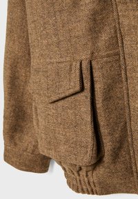 Brun herringbone stofjakke med en lomme og elastisk kant. Jakken har en tekstureret overflade og et diskret mønster.