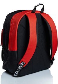 Zaino nero con spallacci imbottiti rossi e superficie testurizzata. Dotato di tasche laterali e una tracolla con marchio. Costruzione in tessuto durevole.