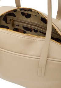 Beżowa skórzana torebka z złotym zamkiem, posiadająca wnętrze w panterkę oraz dwie przegrody, w tym jedną z zamkiem.