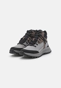 Chaussures de randonnée grises et noires avec une tige texturée, un bout renforcé et une semelle à semelles multidirectionnelles pour une meilleure adhérence.