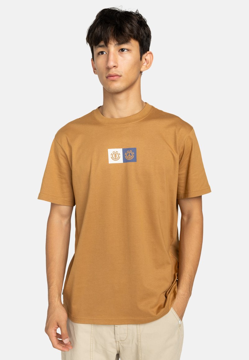 Camiseta de algodón marrón con cuello redondo y mangas cortas. Presenta un pequeño gráfico en blanco y azul en el centro. Textura suave.