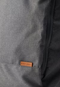 Τσαντάκι από γκρι ύφασμα με υφή στην επιφάνεια, που διαθέτει εμφανές φερμουάρ και ταμπελάκι από ταμπά δέρμα με την επιγραφή «PIER-ONE». Απλός και λειτουργικός σχεδιασμός.