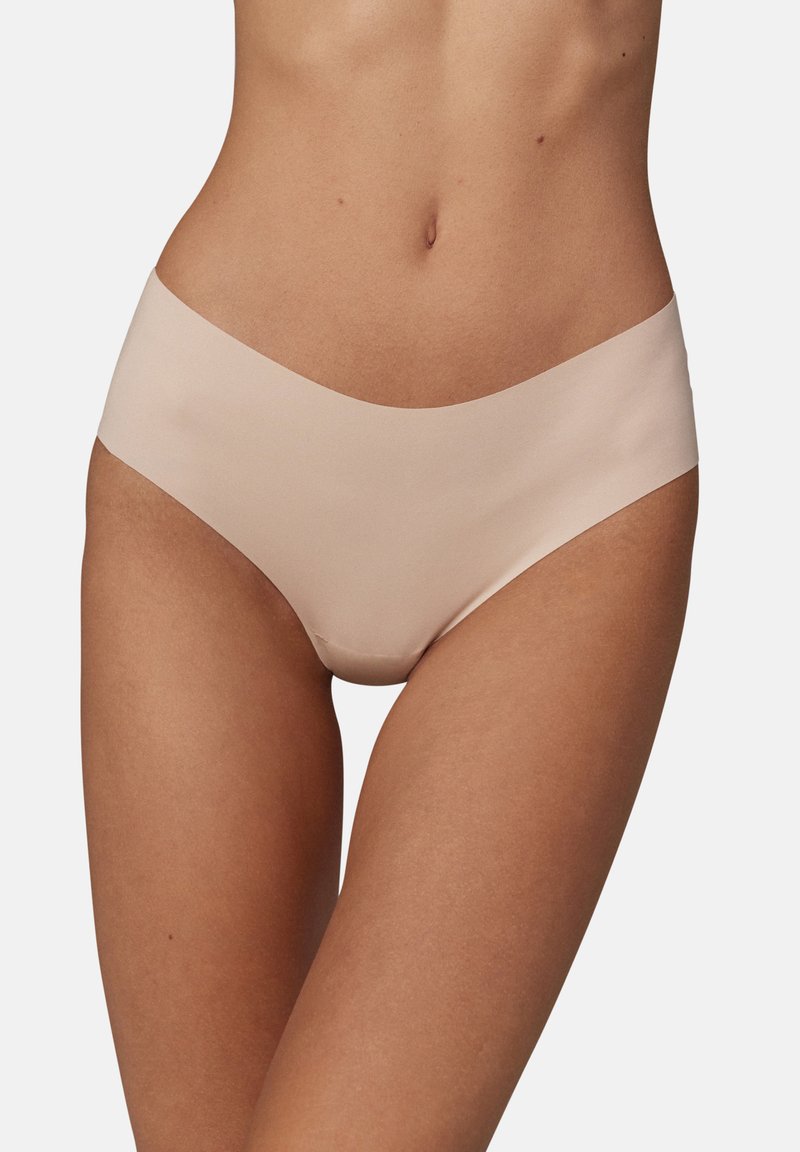 Sous-vêtements hipster beiges sans couture, fabriqués à partir d'un matériau doux avec une texture lisse et une taille basse. Aucune couture ni motif visible.