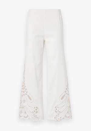 Bredde benbukser lavet af hvidt stof med indviklede beige broderimønstre og bølgede kanter på de nederste ben.