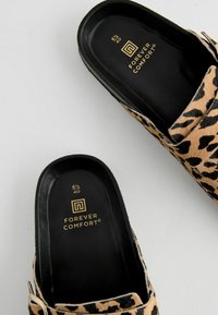 Sandale na klizanje s leopardećim uzorkom i crnom potplatom. Imaju podstavljenu ulošku i zlatni brend unutar. Materijal izgleda mekano i teksturirano.
