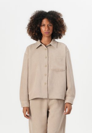 Beige corduroy shirt with a button-down front, relaxed fit, point collar, single chest pocket, and ribbed texture.