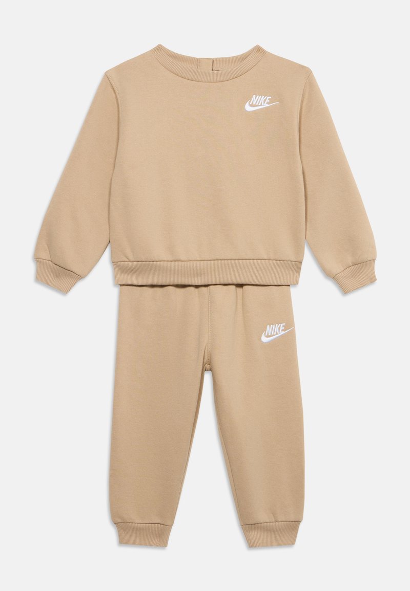 Μπεζ παιδικό σετ φούτερ και παντελονιού Nike με λευκά λογότυπα Nike στο στήθος και στον αριστερό μηρό, ριμπ μανσέτες και τελείωμα, μακριά μανίκια και ελαστική μέση.