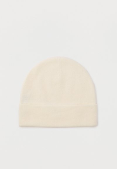 Tej színű kötött sapka hajtott széllel, sima fehér háttér előtt bemutatva.