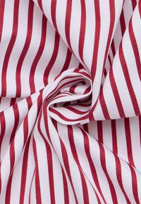 Tessuto di cotone a righe rosse e bianche, caratterizzato da una texture liscia e un motivo a trama fitta. Le righe sono distribuite uniformemente e con una consistenza costante.