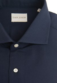 Camisa de vestir azul marino con cuello, botones blancos y una etiqueta "DAN JOHN" cosida en el interior del cuello.