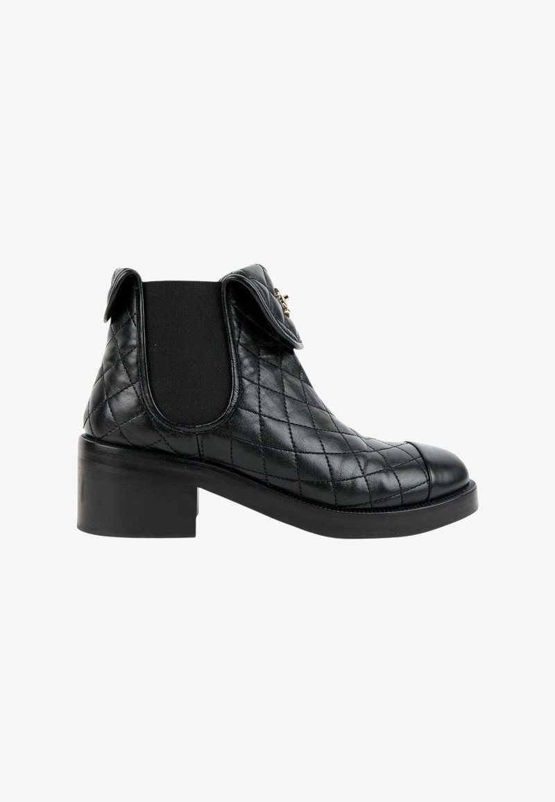 Bottine en cuir noir avec motif matelassé, panneau latéral élastique, petit talon bloc et petit détail de rabat plié près du haut.