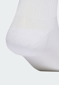 Biela ponožka z bavlnenej zmesi s rebrovanou textúrou, spevnenou pätou a špicou a hladkým povrchom. Tesne prilieha, navrhnutá pre pohodlie a trvanlivosť.