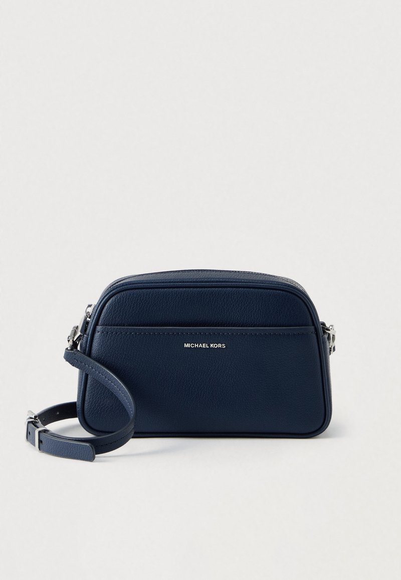 Temno modra usnjena torbica čez telo z teksturirano površino, zadrgo, nastavljivim trakom in srebrnim logotipom spredaj.