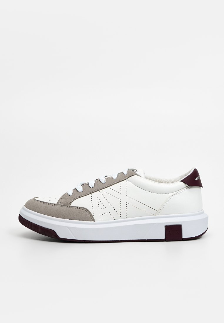 Witte en grijze sneaker met een bovenwerk van leer en suède, vetersluiting, textuurelementen en een subtiele logo detail op de hak.
