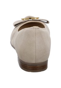 Bailarinas de ante beige con un pequeño tacón, punta redonda y un gran lazo en la parte delantera. Textura suave y detalles de costura sutiles.