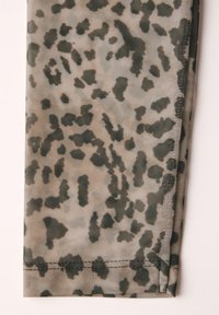 Hieno kangas bežin värin ja tummanvihreän leopardiprintin kanssa. Siinä on sujuva rakenne ja siisti helma, joka esittelee selkeitä, epäsäännöllisiä kuvioita.