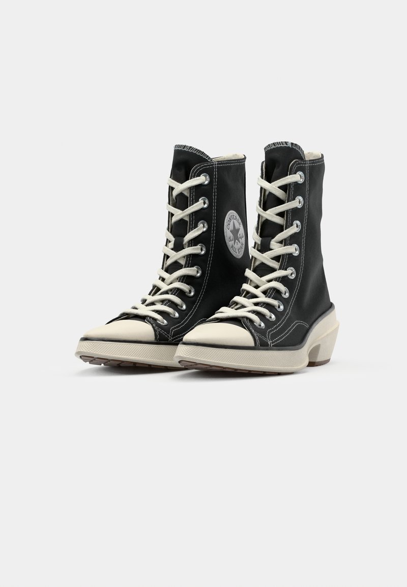 Sneakers alte nere con lacci bianchi, punta in gomma e suola testurizzata. Patch del logo iconico sul lato. Presenta cuciture a contrasto.