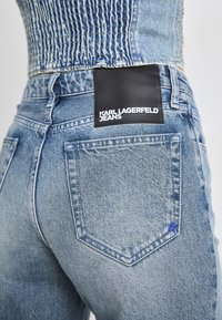 Jeans in denim blu chiaro presentano un classico design a cinque tasche con un'etichetta in pelle sulla tasca posteriore che riporta la scritta "KARL LAGERFELD JEANS."