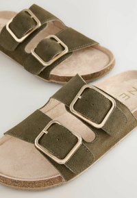 Olijfgroene sandalen van suede, met twee verstelbare banden met gouden gespen en een lichtbruine, gevoerde voetbed.