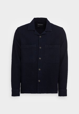 Navy blue linen shirt with a collar, button front, and two chest pockets. Features a textured fabric and long sleeves with buttoned cuffs.